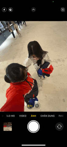 a phone screen shows a person taking a picture of another person on the ice