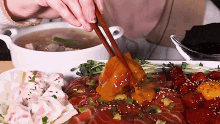 a person is eating a plate of food with chopsticks and a bowl of soup