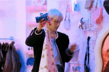 a man in a black jacket is holding a scarf around his neck while standing in front of a mirror in a store .