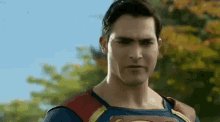 a close up of a man in a superman costume standing in front of trees .