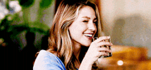 a woman is smiling while drinking a glass of water .