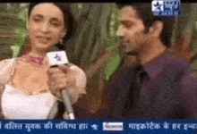 a man is holding a microphone while talking to a woman on a television screen