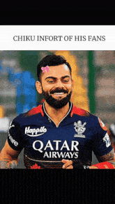 a man with a beard wearing a qatar airways shirt smiles