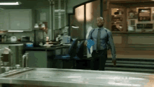 a man in a blue shirt and tie is standing in front of a table