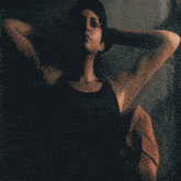 a woman with her hands behind her head is standing in the dark