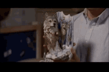 a man is holding a statue of a wolf and a dog .