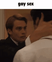 a man in a suit and tie is hugging another man in a room .