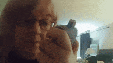 a woman wearing glasses is holding a cell phone