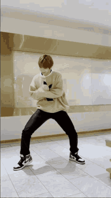 a man in a tan sweater and black jeans is dancing