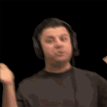 a man wearing headphones and a microphone is making a funny face on a black background .