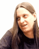 a man with long hair is smiling and wearing a black shirt