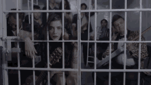 a group of people are behind bars in a jail
