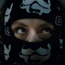 a close up of a person wearing a mask with letters g on it
