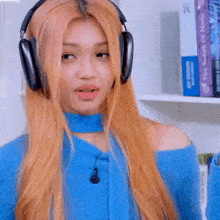 a woman with long blonde hair wearing headphones and a blue sweater .