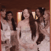 a group of women are standing around a girl in a white dress .