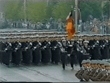 a group of soldiers marching down a street with a flag flying in the background