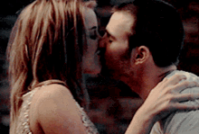 a man and a woman are kissing in front of a wall