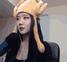 a woman wearing a stuffed chicken hat is talking into a microphone