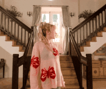 a woman wearing a pink sweater with red butterflies on the sleeves