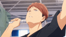 a man with red hair and a black shirt is holding a badminton racket
