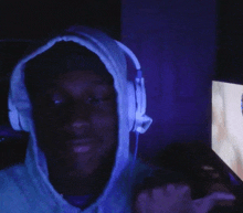 a man wearing headphones and a hoodie is looking at a computer screen