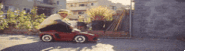 a man is riding a red toy car on a street .