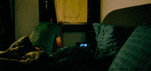 a person laying in bed with a digital clock displaying the time as 22:10