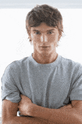 a man wearing a grey t-shirt has his arms crossed