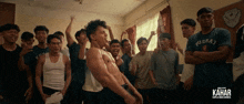 a group of young men are standing in a room with the word kahar on the bottom right