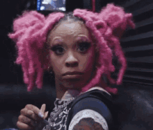 a woman with pink dreadlocks is holding a piece of ice cream