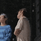 a man and a woman are standing next to each other and looking up .