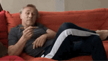 a man is laying on a couch smoking a cigar and looking at his phone .