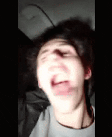 a young man is making a funny face with his mouth open in a car .