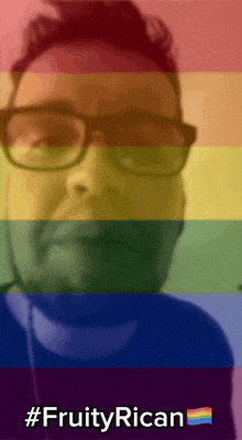a man with glasses and a rainbow flag behind him