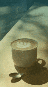 a cup of coffee on a table with a spoon in it