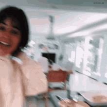 a blurry picture of a woman standing in a kitchen smiling at the camera .