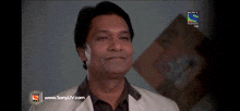 a man is smiling in front of a sony tv screen