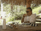 a man sits at a table drinking a drink