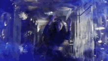 a woman is standing in a dark room with blue lights behind her