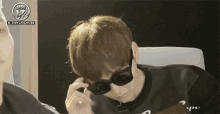 a man wearing sunglasses is sitting in a chair and looking down .