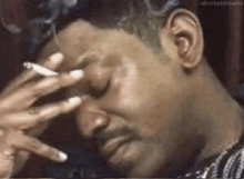a man is smoking a cigarette and covering his face .