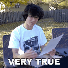 a young man is holding a piece of paper and the words very true are above him