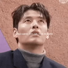 a man wearing a suit and a turtleneck is looking up .