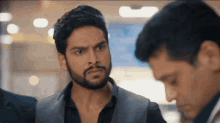 a man with a beard is standing next to another man and making a funny face .