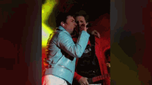 a man in a red jacket is talking to another man in a green shirt