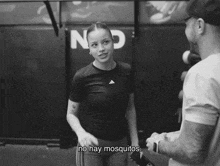 a black and white photo of a woman talking to a man with the words no hay mosquitos in the corner