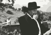 a man in a cowboy hat is smoking a cigarette in a black and white photo