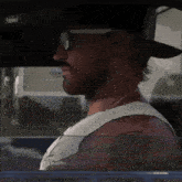 a man wearing sunglasses and a hat is looking out the window of a car