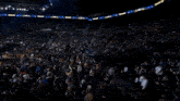 a crowd in a stadium watching a show with a crown on the screen