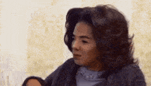 a woman with long hair is sitting on a bed and looking at the camera .